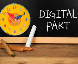 Schultafel mit Schrift "Digital Pakt" darauf, sowie einer selbst gebastelten Uhr und Kreide und Stiften