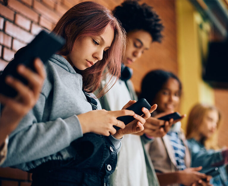 Jugendliche nutzen ihre Smartphones gemeinsam in einem Schulgebäude.