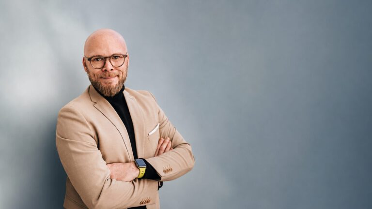 Porträt des Interviewpartners vor schlichtem blau-grauem Hintergrund zum Thema digitale Bildung und DigitalPakt 2.0.